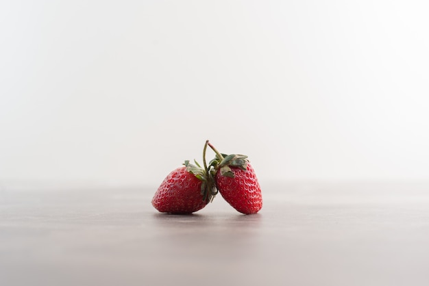 Dos fresas frescas en la mesa de mármol.