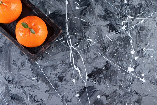 Dos frutas naranjas frescas enteras sobre una tabla de madera.