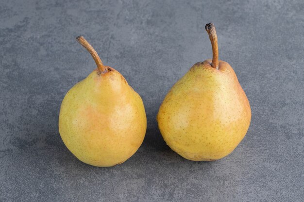 Dos frutos maduros de pera amarillo rojo aislado sobre una superficie gris