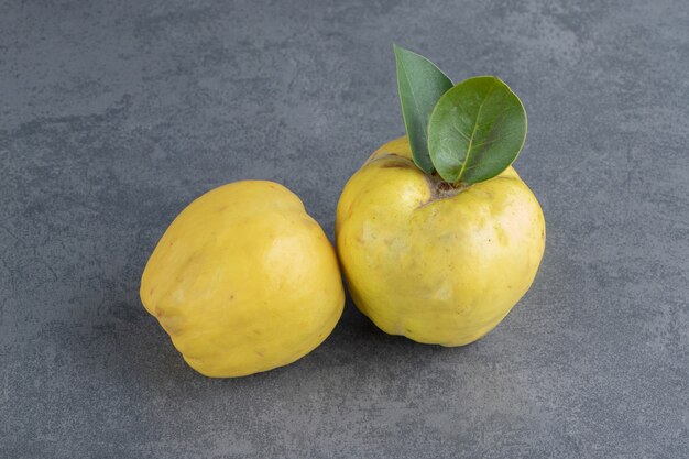 Dos frutos de membrillo crudos aislados sobre una superficie gris