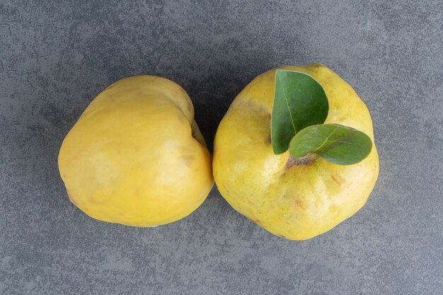 Dos frutos de membrillo crudos aislados sobre una superficie gris