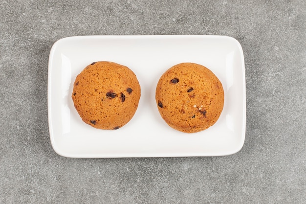 Dos galletas de chocolate en un plato blanco.