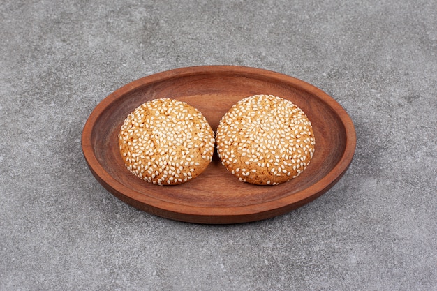 Dos galletas con semillas de sésamo en placa de madera