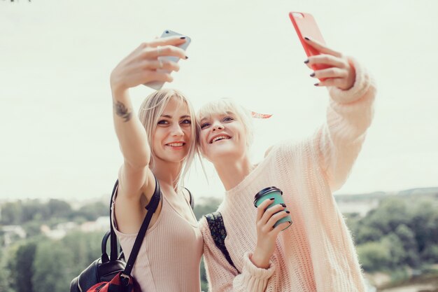 Dos hermanas de chicas jóvenes posando en la calle, hacen selfie