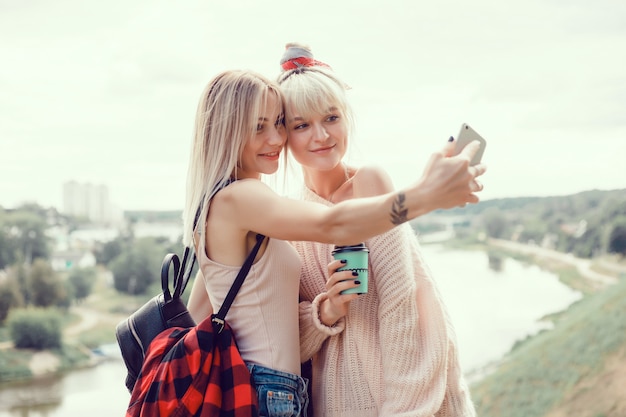Dos hermanas de chicas jóvenes posando en la calle, hacen selfie