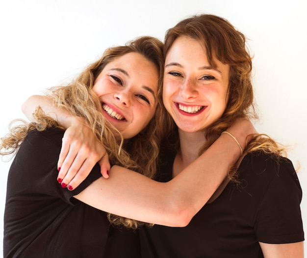 Foto gratuita dos hermanas jóvenes abrazándose contra el fondo blanco