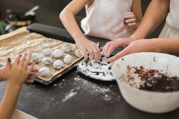 Dos hermanas y madre preparando galletas de chocolate en la cocina