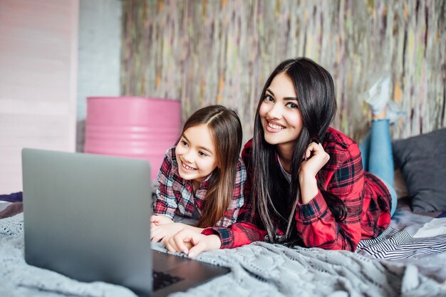 Dos hermanas de pelo negro de la edad preescolar y la adolescencia usando la computadora portátil estudiando juntas