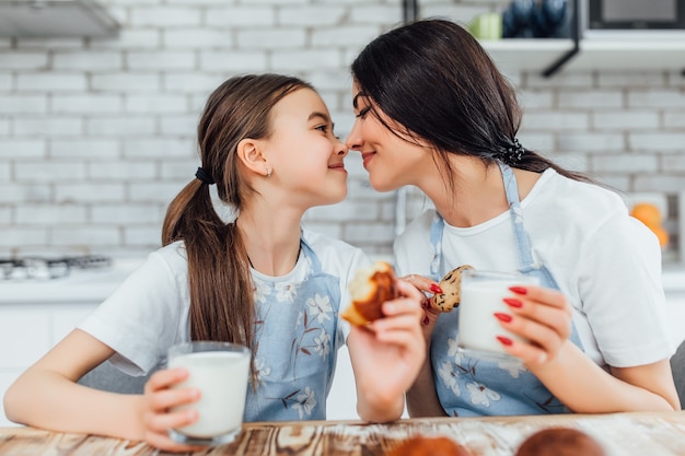 Dos hermanas, sonriendo mientras prueban sus muffins y beben leche.