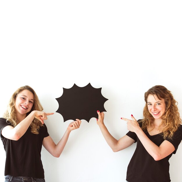 Dos hermanas sonrientes que sostienen la burbuja negra del discurso que señala los dedos