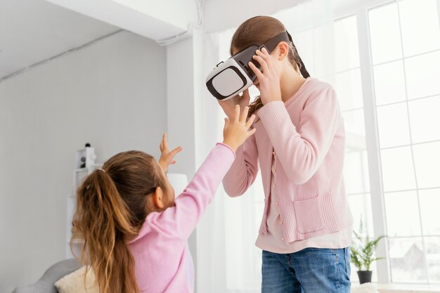 Dos hermanitas en casa jugando con casco de realidad virtual