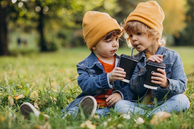 Dos hermanitos sentados en la hierba y bebiendo té