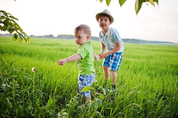 Dos hermanos caminando tomados de la mano en el campo verde hermano amor