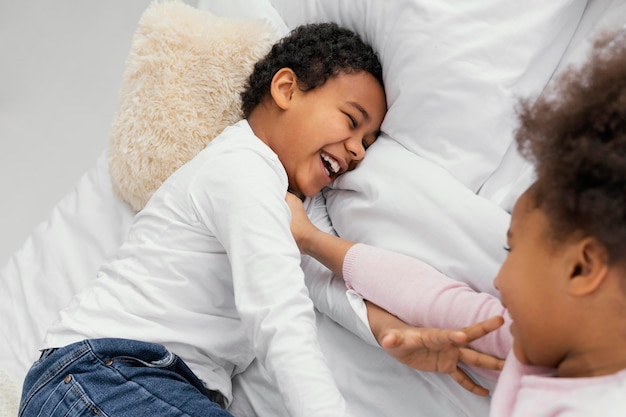 Dos hermanos jugando en la cama en casa