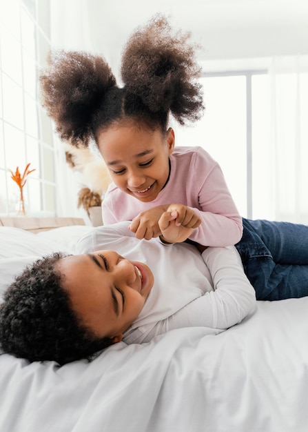 Foto gratuita dos hermanos jugando en casa en la cama juntos