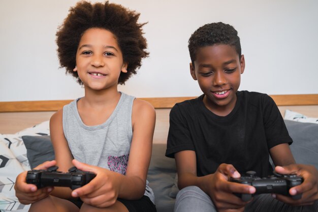 Dos hermanos jugando videojuegos en casa.