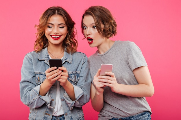 Dos hermosas amigas charlando por teléfonos.