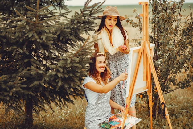 Dos hermosas chicas dibujando en un campo