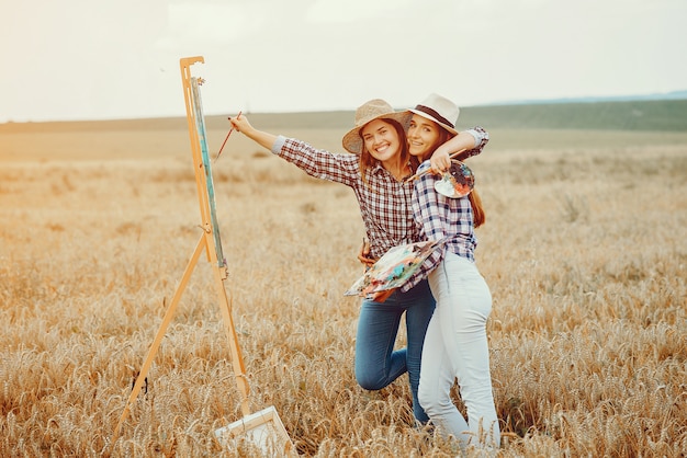 Dos hermosas chicas dibujando en un campo