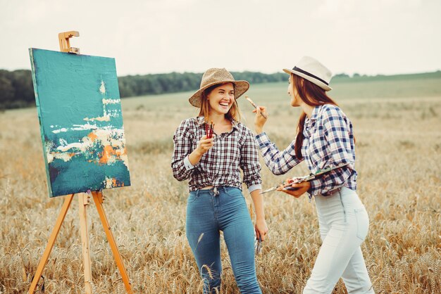 Dos hermosas chicas dibujando en un campo