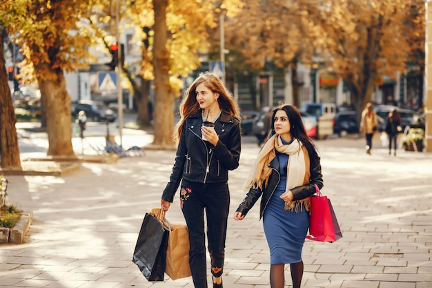 Dos hermosas chicas elegantes caminando por la ciudad con bolsas de compras