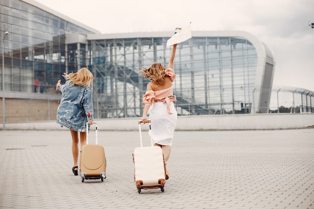 Dos hermosas chicas de pie junto al aeropuerto