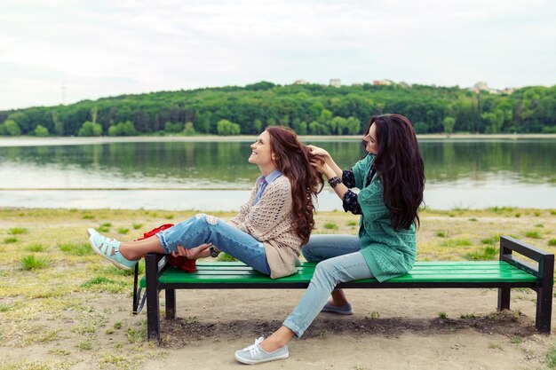 Dos hermosas chicas relajantes mientras hacen el peinado disfrutando del tiempo juntas