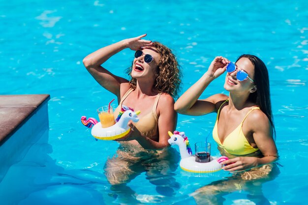 Dos hermosas chicas en traje de baño en la piscina.