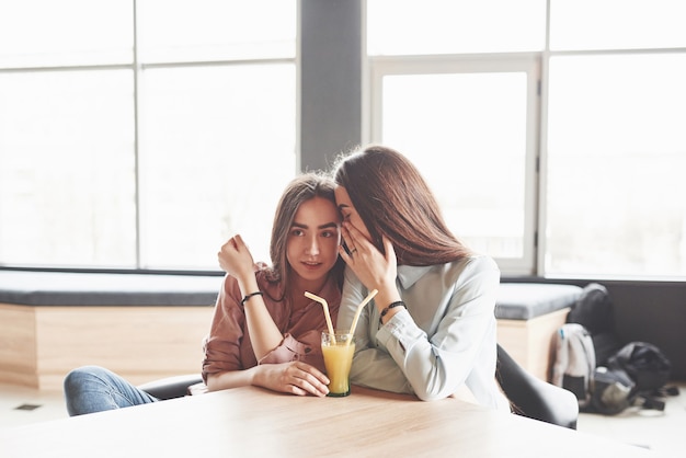 Foto gratuita dos hermosas gemelas pasan tiempo bebiendo jugo.