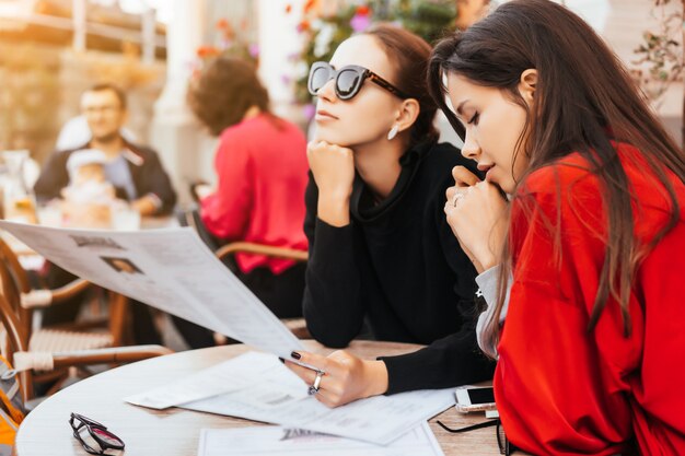 Dos hermosas mujeres con estilo sentado a la mesa en la calle cafe