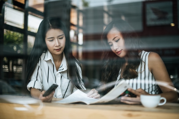 Dos hermosas mujeres hablando todo juntos en la cafetería cafetería