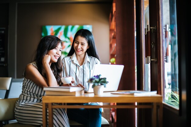 Dos hermosas mujeres hablando todo juntos en la cafetería cafetería