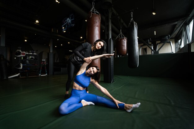 Dos hermosas mujeres jóvenes haciendo fitness en un gimnasio