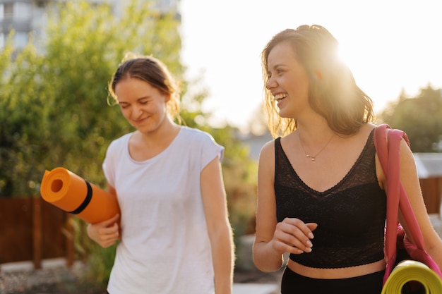 Dos hermosas mujeres jóvenes en ropa deportiva que van a hacer entrenamiento deportivo, gimnasia, yoga