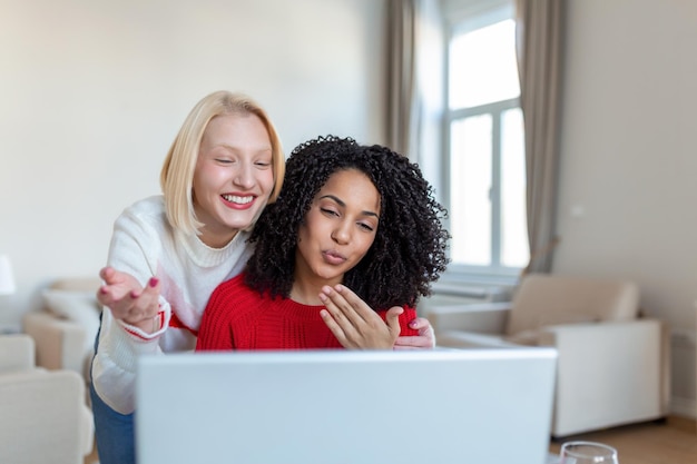 Dos hermosas mujeres que usan una computadora portátil para una videollamada en línea y un brindis en línea con sus amigos Fiesta en línea para amigos