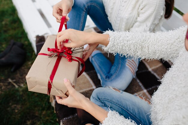 Dos hermosas mujeres sentadas en un banco y sosteniendo en sus manos regalos, vista cercana