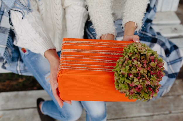 Dos hermosas mujeres sentadas en un banco y sosteniendo en sus manos regalos, vista cercana