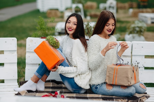 Dos hermosas mujeres sentadas en un banco y sosteniendo en sus manos regalos