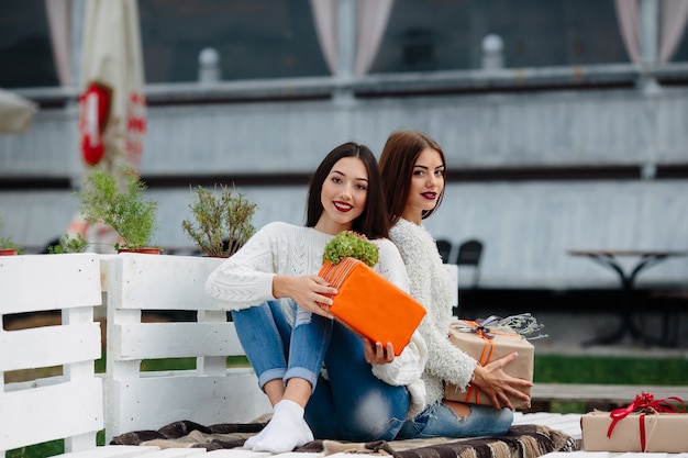 Dos hermosas mujeres sentadas en un banco y sosteniendo en sus manos regalos