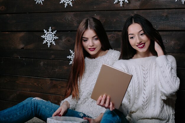 Dos hermosas mujeres sentadas en el suelo con una tableta