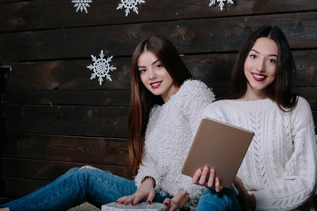 Dos hermosas mujeres sentadas en el suelo con una tableta