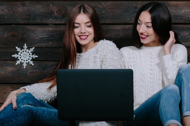 Dos hermosas mujeres ubicadas en el suelo con una computadora portátil