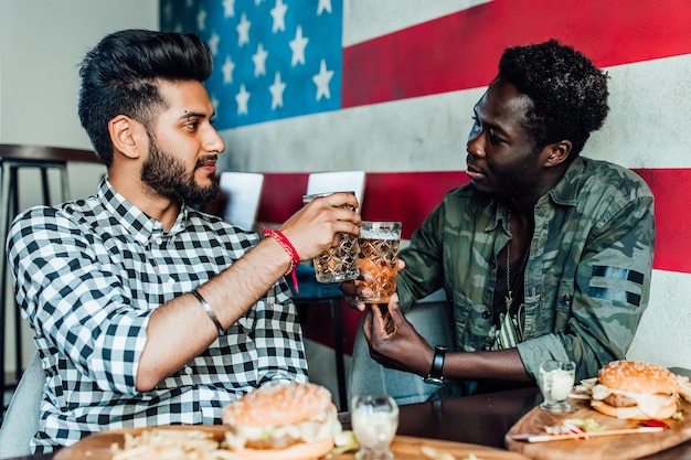 Dos hombre alegre divirtiéndose mientras pasa tiempo con amigos en un pub y bebiendo cerveza.