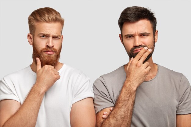 Dos hombres concentrados pensativos pensativos sostienen la barbilla, tratan de encontrar la solución adecuada o hacen planes