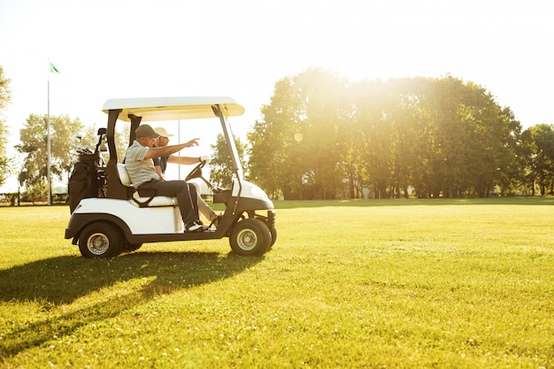 Dos hombres golfistas conduciendo en un carrito de golf