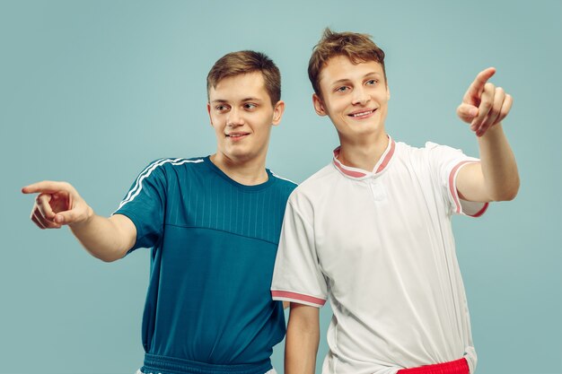 Dos hombres jóvenes en ropa deportiva aislados. Aficionados al deporte, fútbol o club o equipo de fútbol. Retrato de medio cuerpo de amigos. Concepto de emociones humanas, expresión facial.