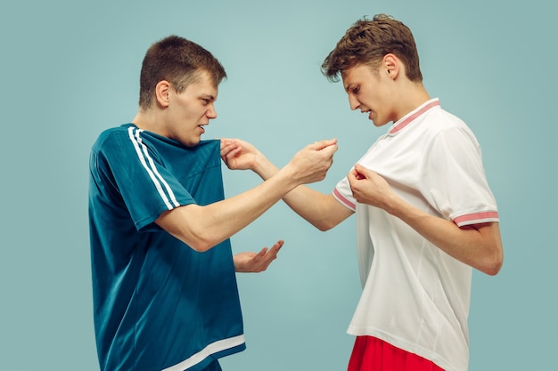 Dos hombres jóvenes en ropa deportiva aislados. Aficionados al deporte, fútbol o club o equipo de fútbol. Retrato de medio cuerpo de amigos. Concepto de emociones humanas, expresión facial.