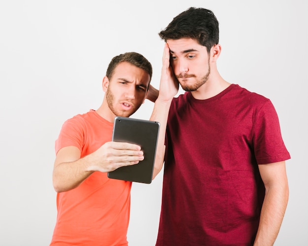 Foto gratuita dos hombres mirando desconcertados a la pantalla de la tableta