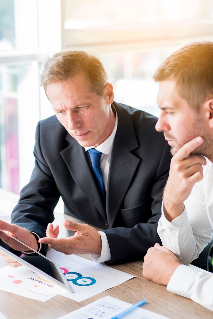 Foto gratuito dos hombres de negocios discutiendo plan de negocios en tableta digital