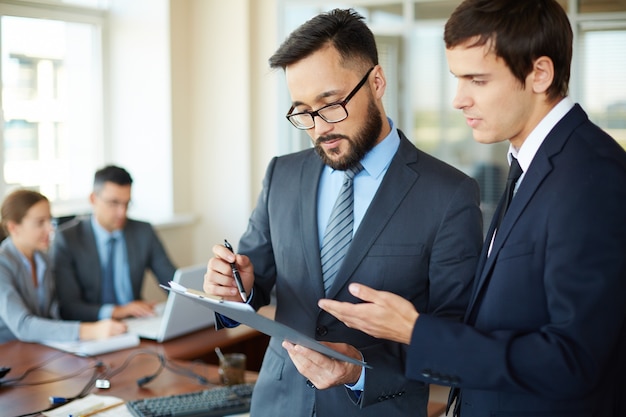 Foto gratuita dos hombres de negocios jóvenes con un informe